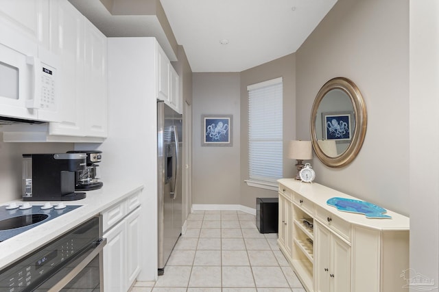 kitchen with stainless steel refrigerator with ice dispenser, white cabinetry, wall oven, and light tile patterned floors