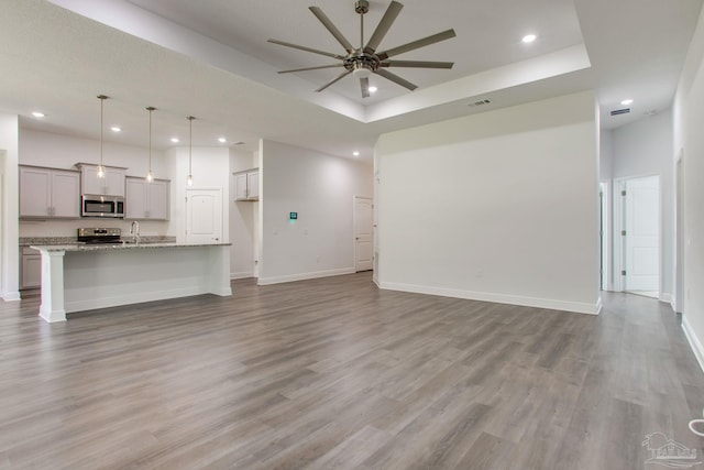 1825 Peace Ter, Cantonment, FL 32533 - unfurnished living room featuring recessed lighting, a tray ceiling, a sink, light wood-type flooring, and ceiling fan