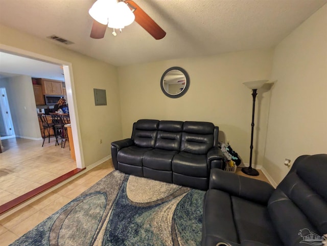 living room featuring ceiling fan, a textured ceiling, and light tile patterned floors