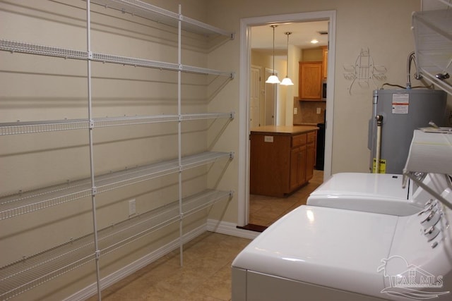 laundry area featuring water heater, washer and dryer, and light tile patterned floors