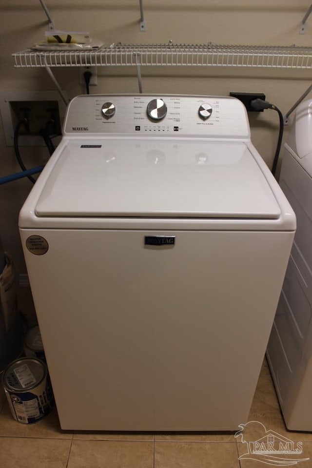 clothes washing area with light tile patterned flooring and washer / clothes dryer