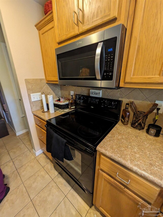 kitchen with black electric range oven, light tile patterned floors, and backsplash