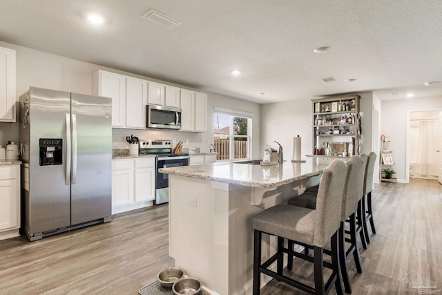 10869 Blacktail Loop, Pensacola, FL 32526 - kitchen with stainless steel appliances, a sink, light wood-type flooring, white cabinetry, and a textured ceiling