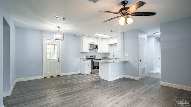 kitchen with white cabinetry, sink, stainless steel appliances, kitchen peninsula, and hardwood / wood-style flooring