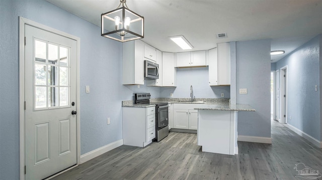 kitchen featuring stainless steel appliances, sink, wood-type flooring, decorative light fixtures, and white cabinets