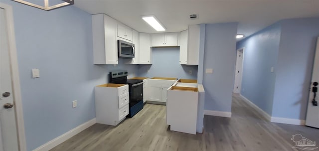 kitchen with white cabinets, light hardwood / wood-style flooring, and black / electric stove