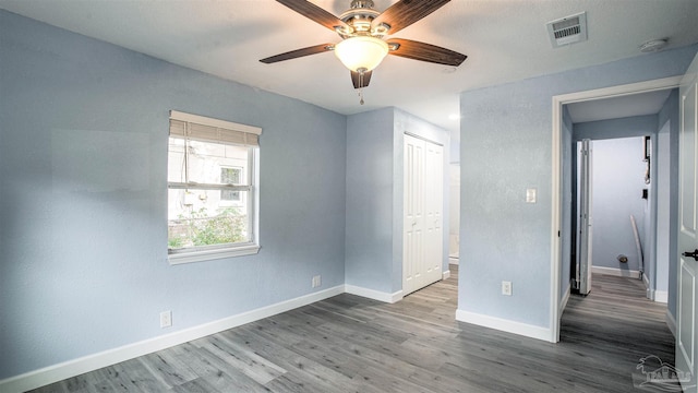 unfurnished bedroom with ceiling fan, a closet, and hardwood / wood-style flooring