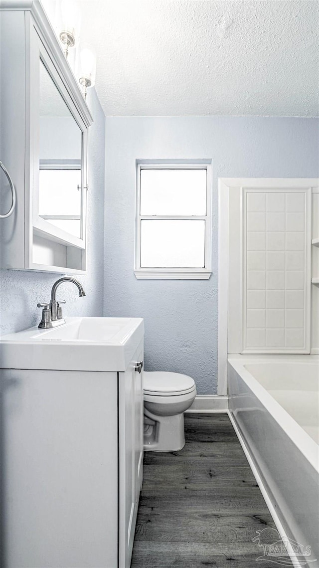 bathroom featuring vanity, hardwood / wood-style flooring, toilet, and a tub