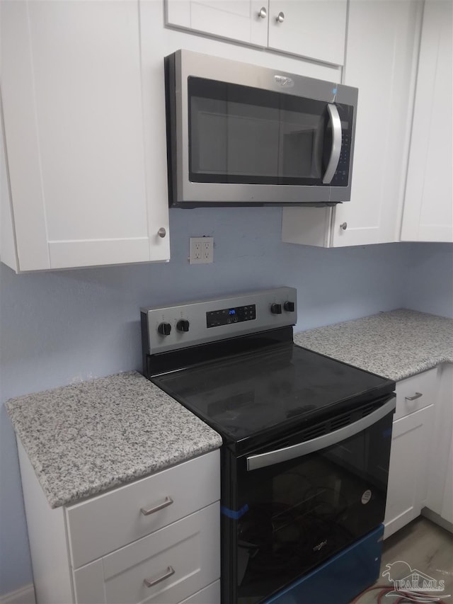 kitchen with white cabinetry, light stone countertops, and appliances with stainless steel finishes