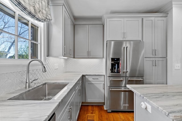 kitchen with tasteful backsplash, gray cabinetry, a sink, light stone countertops, and high end refrigerator