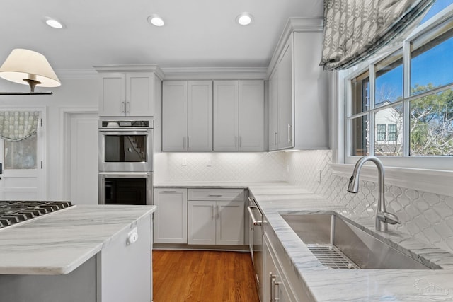 kitchen featuring stainless steel appliances, light stone counters, a sink, and decorative backsplash