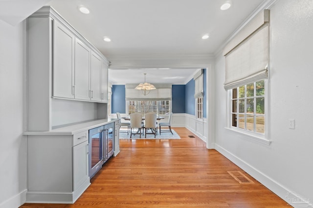 kitchen with light wood-style flooring, visible vents, white cabinetry, light countertops, and ornamental molding