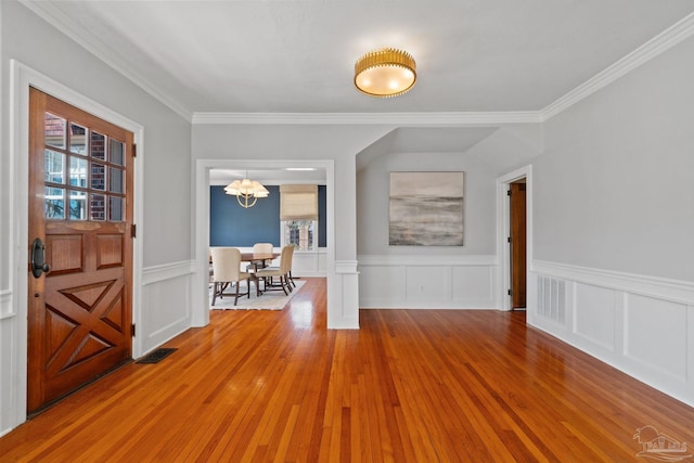 entrance foyer featuring light wood finished floors, visible vents, a chandelier, and crown molding