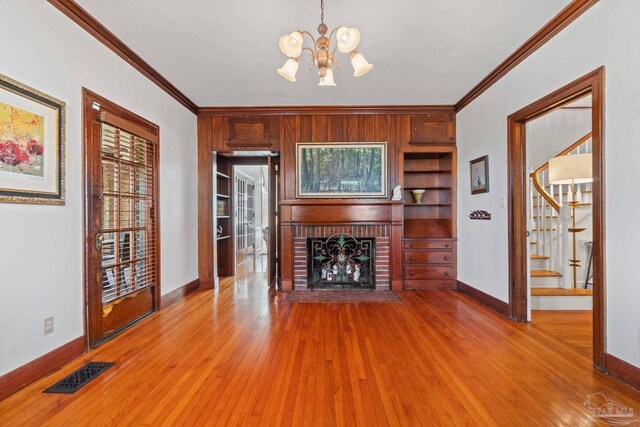 unfurnished living room with visible vents, crown molding, a fireplace, and wood finished floors