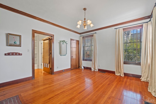 spare room featuring baseboards, light wood-style flooring, a chandelier, and crown molding