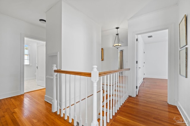 hallway featuring hardwood / wood-style floors, an upstairs landing, and baseboards