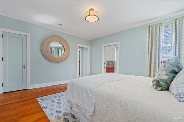 bedroom with ornamental molding, wood finished floors, and baseboards