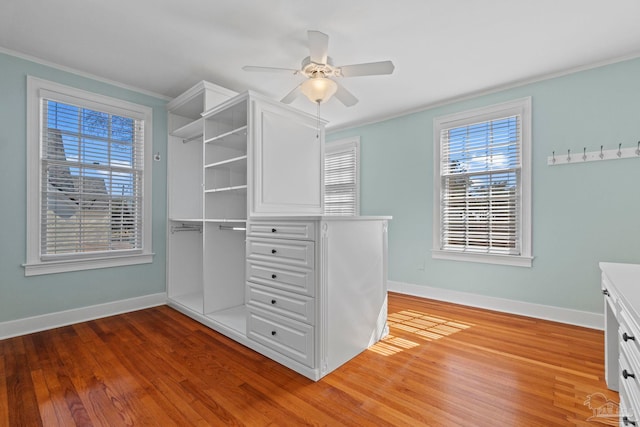 walk in closet with light wood-style floors and a ceiling fan