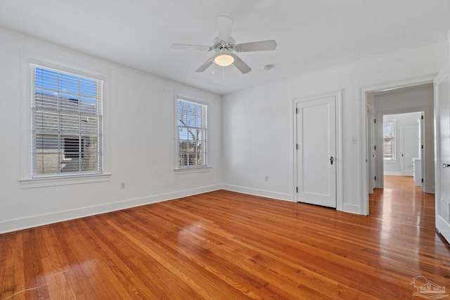 spare room with baseboards, ceiling fan, and light wood finished floors