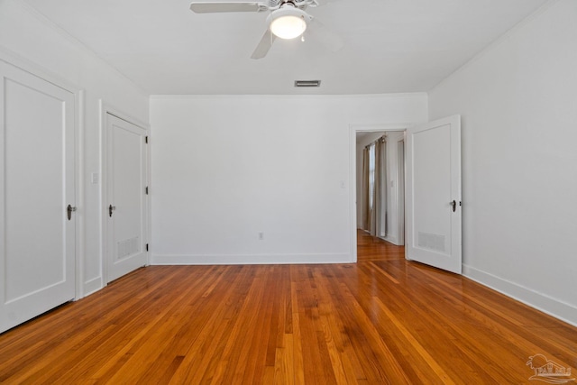 unfurnished bedroom with ornamental molding, visible vents, baseboards, and wood finished floors