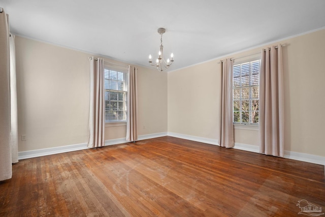 spare room featuring hardwood / wood-style floors, a notable chandelier, ornamental molding, and a wealth of natural light