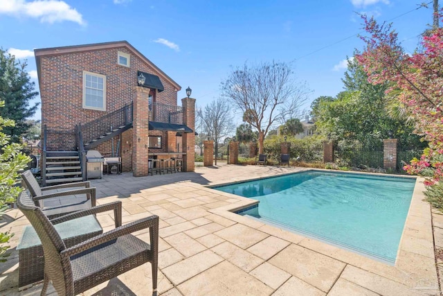 outdoor pool featuring stairs, outdoor dry bar, and a patio