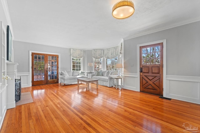 foyer with french doors, a wainscoted wall, a fireplace, and hardwood / wood-style floors