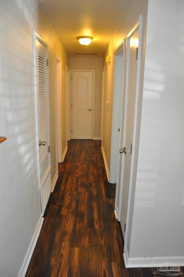 corridor featuring baseboards and wood finished floors