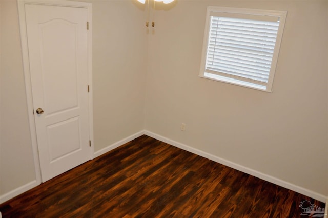 spare room featuring baseboards and dark wood-type flooring