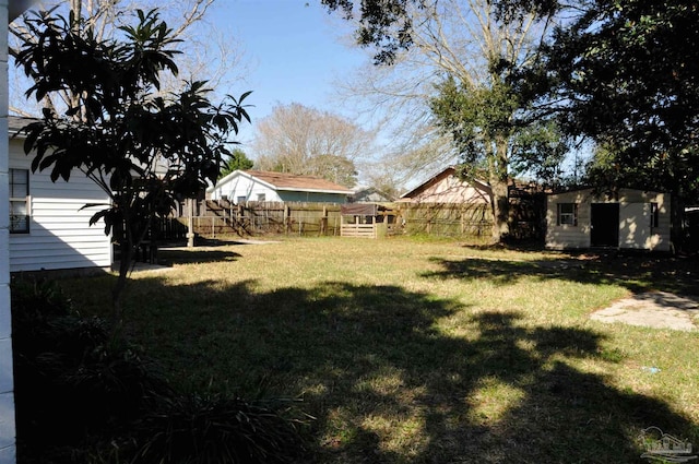 view of yard with a storage shed, an outdoor structure, and fence