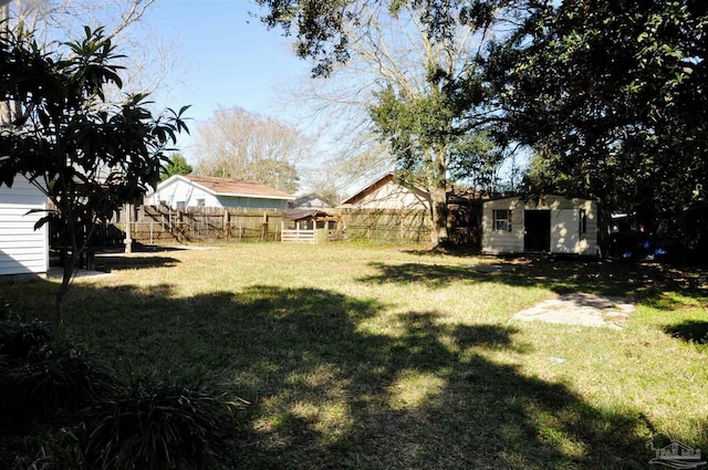 view of yard featuring a storage shed, an outdoor structure, and a fenced backyard