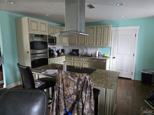 kitchen with a center island, a textured ceiling, appliances with stainless steel finishes, island exhaust hood, and cream cabinets