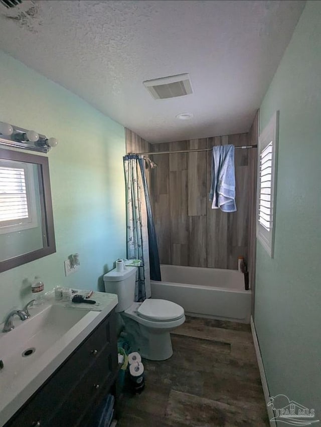 full bathroom featuring shower / bathtub combination with curtain, vanity, wood-type flooring, a textured ceiling, and toilet