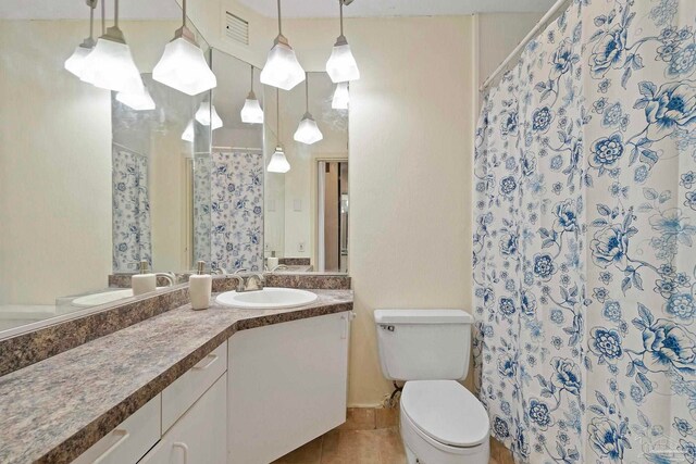 bathroom with vanity, toilet, curtained shower, and tile patterned flooring