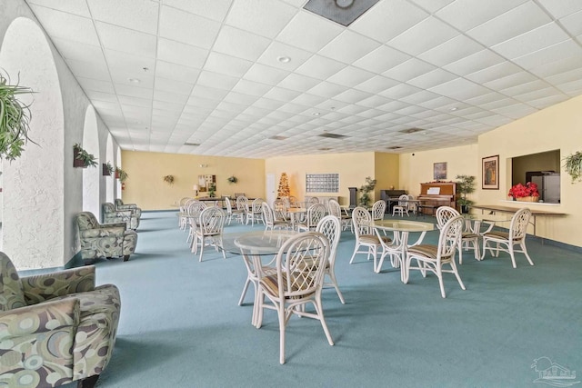 carpeted dining room featuring a drop ceiling