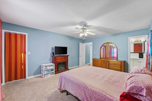 bedroom with ceiling fan, a textured ceiling, ensuite bathroom, and carpet floors