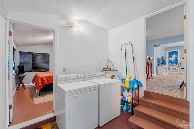 washroom featuring water heater, separate washer and dryer, and a textured ceiling