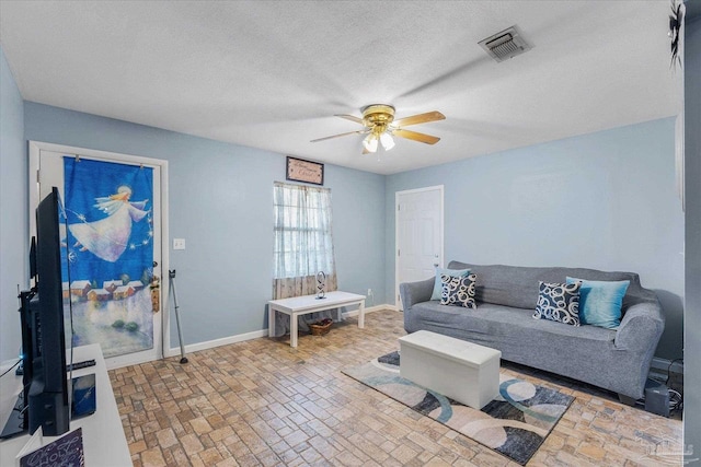 living room featuring ceiling fan and a textured ceiling