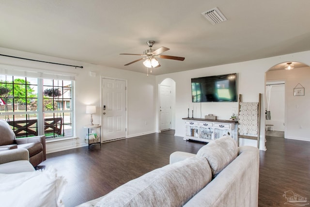 living area featuring arched walkways, visible vents, and wood finished floors