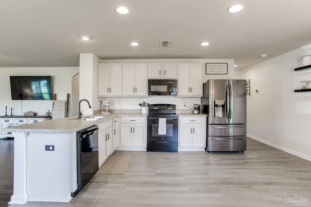 kitchen featuring white cabinets, a sink, a peninsula, visible vents, and black appliances