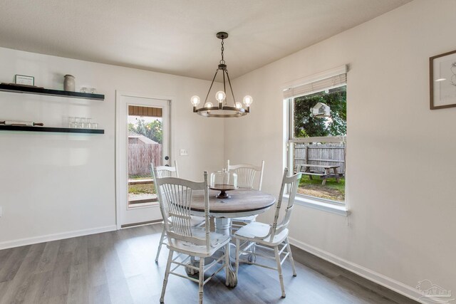 dining area featuring an inviting chandelier, a healthy amount of sunlight, and wood finished floors