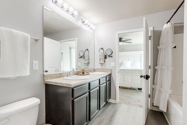 bathroom featuring double vanity, toilet, a sink, and wood finished floors