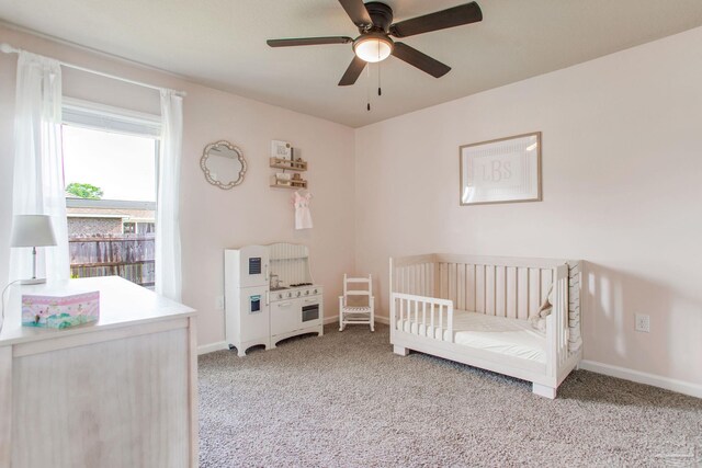 bedroom with a nursery area, baseboards, and carpet