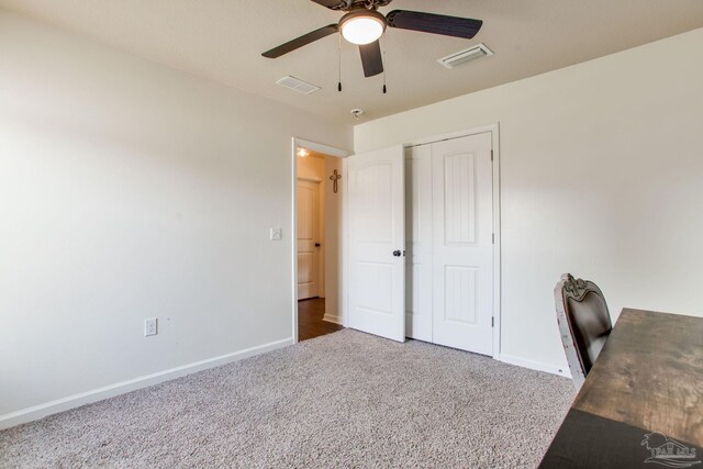 unfurnished office with carpet floors, ceiling fan, baseboards, and visible vents