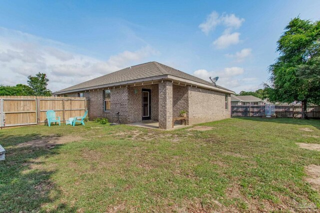 back of house with a fenced backyard, a yard, and brick siding