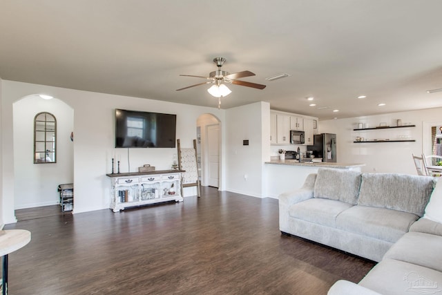 living room featuring baseboards, arched walkways, dark wood-type flooring, and recessed lighting