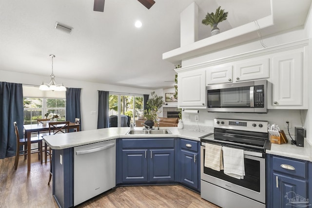 kitchen with white cabinets, blue cabinets, sink, and appliances with stainless steel finishes