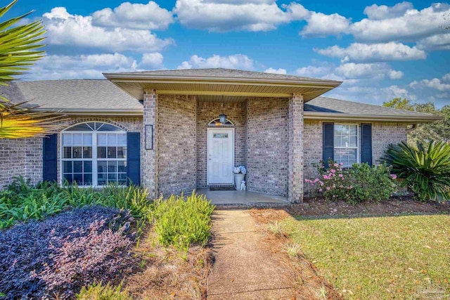 doorway to property featuring a lawn and covered porch