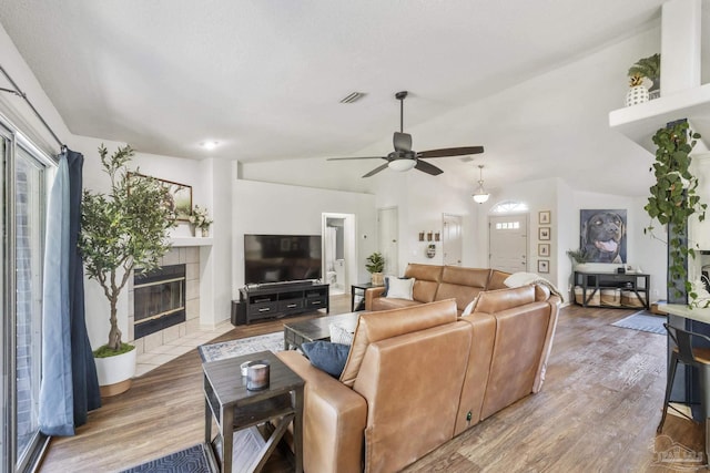 living room featuring a fireplace, wood-type flooring, ceiling fan, and lofted ceiling