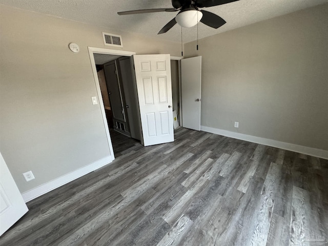 unfurnished bedroom with dark wood-style flooring, visible vents, a textured ceiling, and baseboards